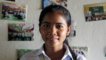 Nuori nepalilainen opiskelijatyttö Srey Ny katsoo kameraan huoneessaan.