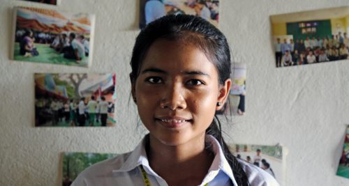 Nuori nepalilainen opiskelijatyttö Srey Ny katsoo kameraan huoneessaan.