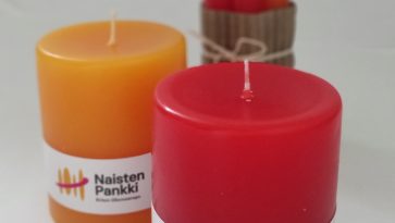 Kuvassa kaksi pyötäkynttilää ja taustalla nippu korkeita kynttilöitä