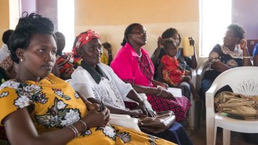 Ryhmä afrikkalaisia naisia istuu kuuntelemassa kirkossa kuuntelemassa rauhanneuvotteluja.
