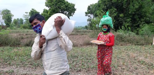 Nepalilainen mies kantaa ruokasäkkiä ja takana kävelevällä naisella on pään päällä jauhopussi.