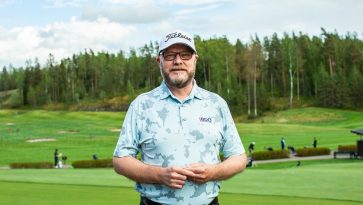 Mies lippalakkipäässä seisoo golfkentällä ja katsoo kameraan.