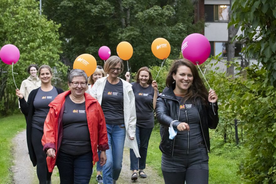 JOukko naisia värikkäiden ilmapallojen kera.