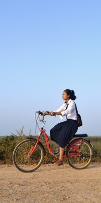 tyttö ajaa polkupyörällä tietä pitkin