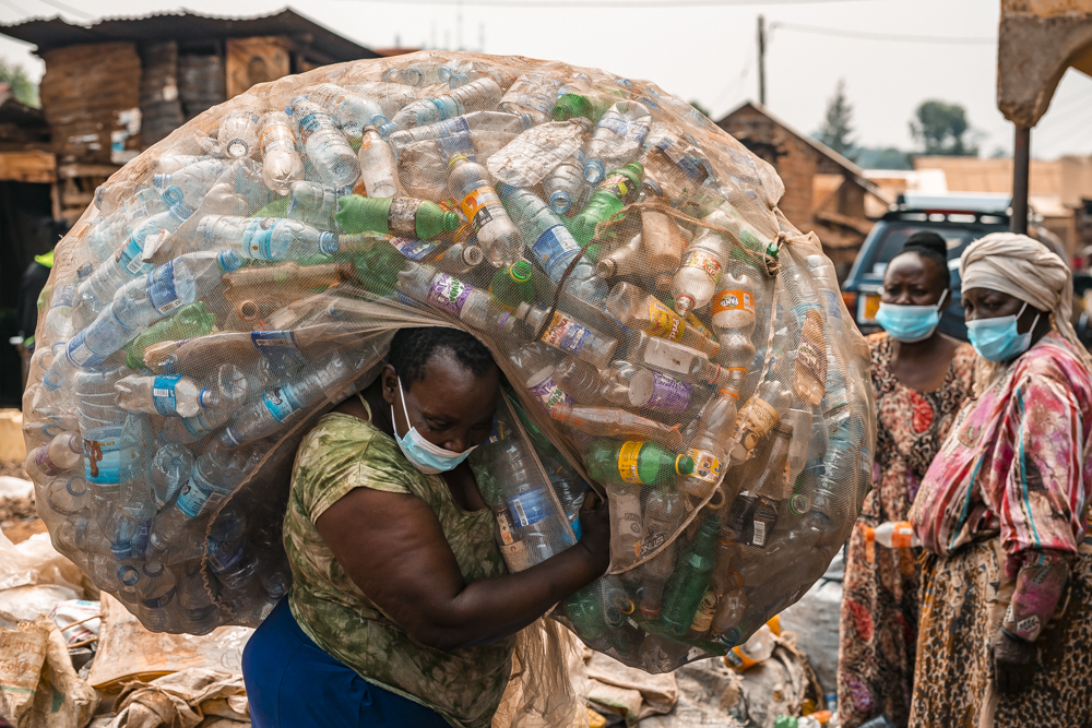 nainen kantaa valtavaa säkillistä tyhjiä muovipulloja