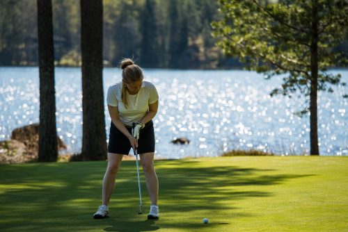 Nainen golfaamassa veden äärellä.