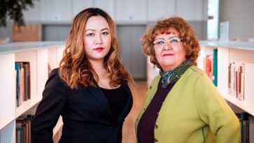 Kaksi naista seisoo kinnakkain kirjahyllyjen välissä.