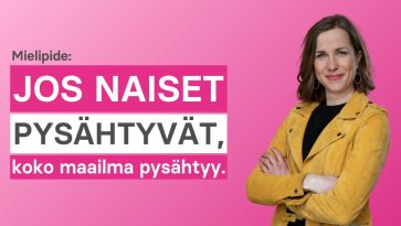 Nainen oranssissa takissa käsivarret ristissä vyötäröllä.