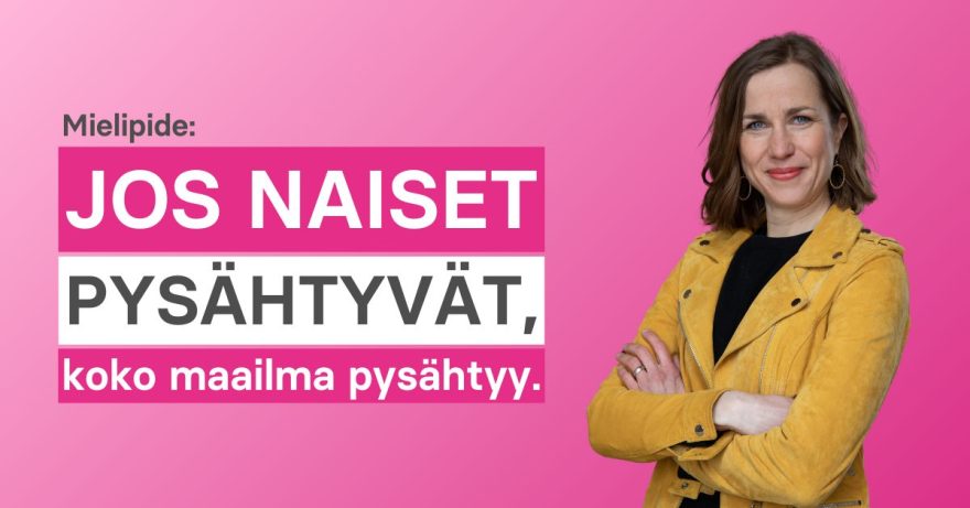 Nainen oranssissa takissa käsivarret ristissä vyötäröllä.