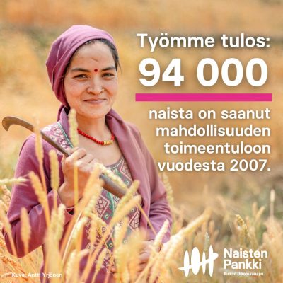 Nainen viljapellolla lila huivi päässään.