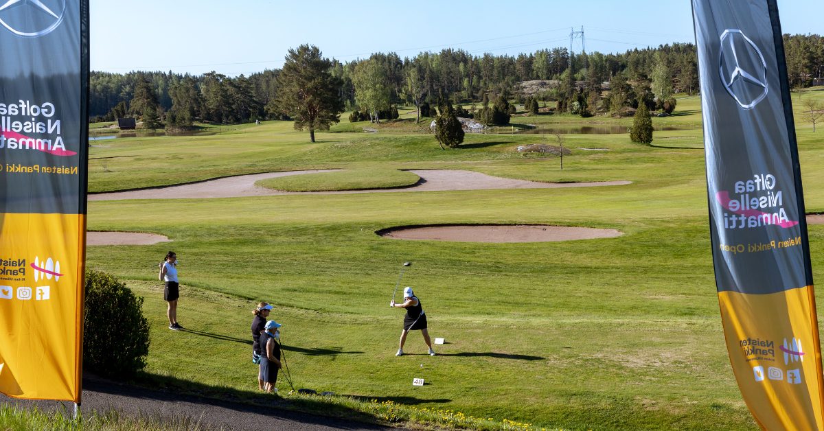 Nainen lyömässä palloa golf-kentällä.