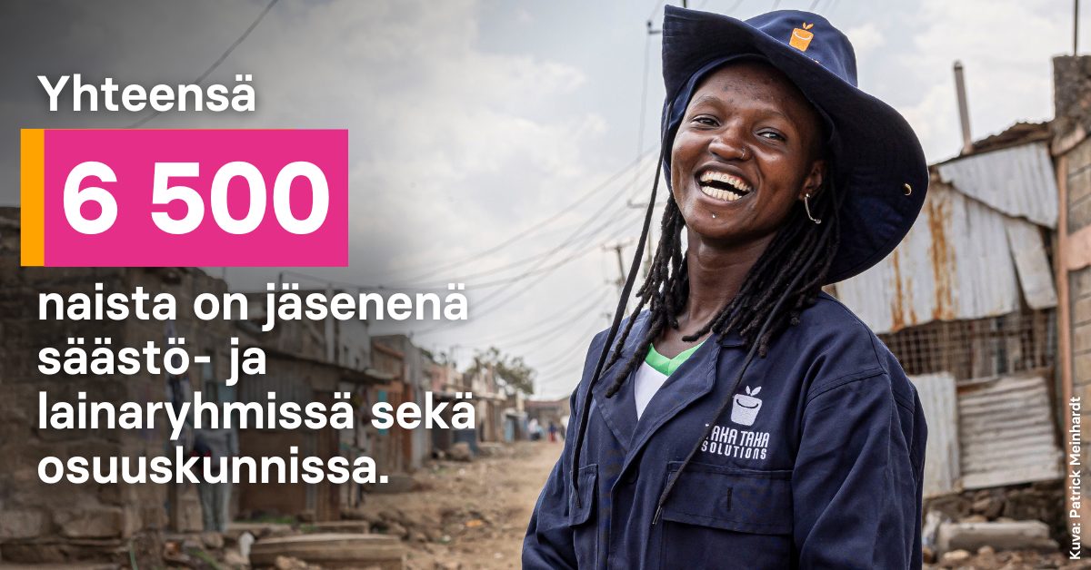 Nainen haalareissa ja hattu päässä hymyilee leveästi.