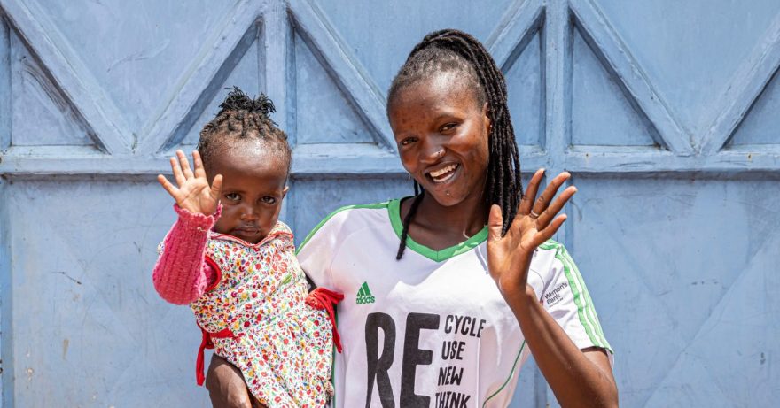 Nainen lapsi sylissä vilkuttaa.