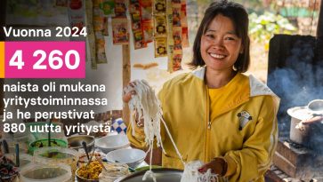 nainen keltaisessa paidassa pitää käsissään nuudeleita ja hymyilee