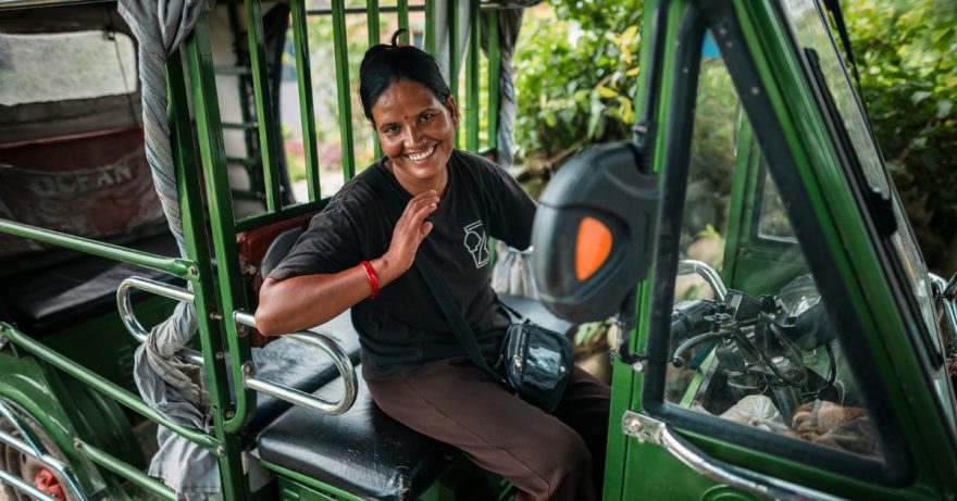 Nainen heiluttaa kättään sähköauton etuistuimella.