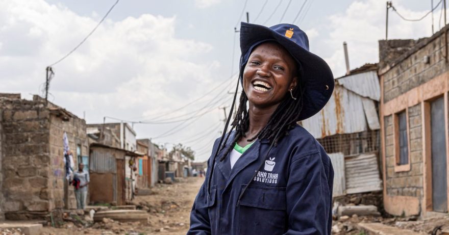 nainen hatussa ja haalarissa nauraa