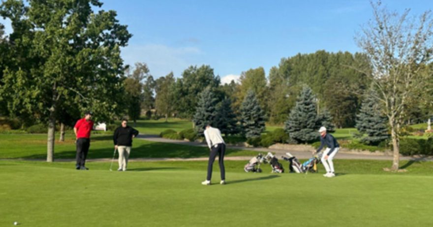 Kaksi ihmistä golfaamassa vihreällä kentällä.