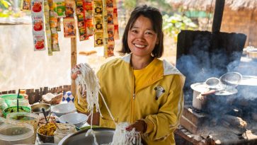 Nainen katukeittiössä nuudeleita käsissään.