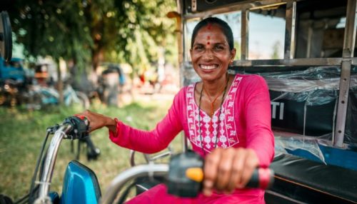 Nainen hymyilee tuk-tuk moottoriajoneuvon ratissa.