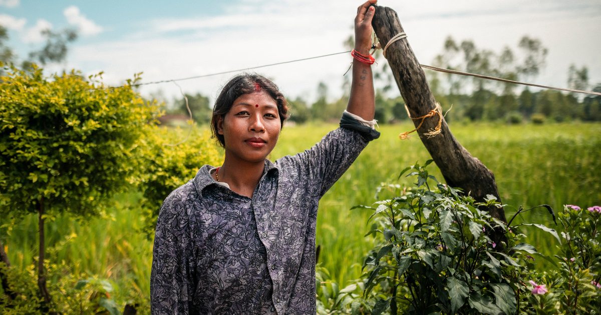 Nainen nojaa aidantolppaan.