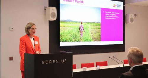 Nainen puhujapöntössä takanaan kuvaesitys.