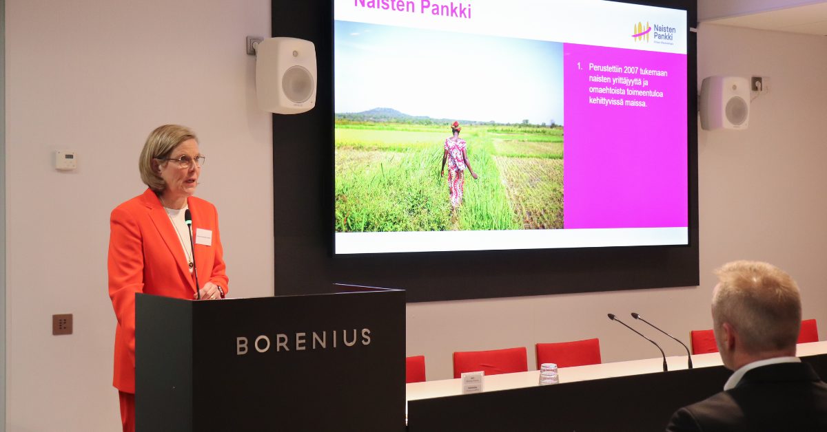 Nainen puhujapöntössä takanaan kuvaesitys.