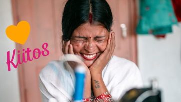 Nainen nauraa kädet poskillaan.