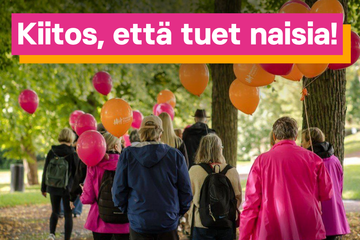 Joukko ihmisiä kävelemässä pinkkien ja oranssien ilmapallojen kanssa pois päin kamerasta.